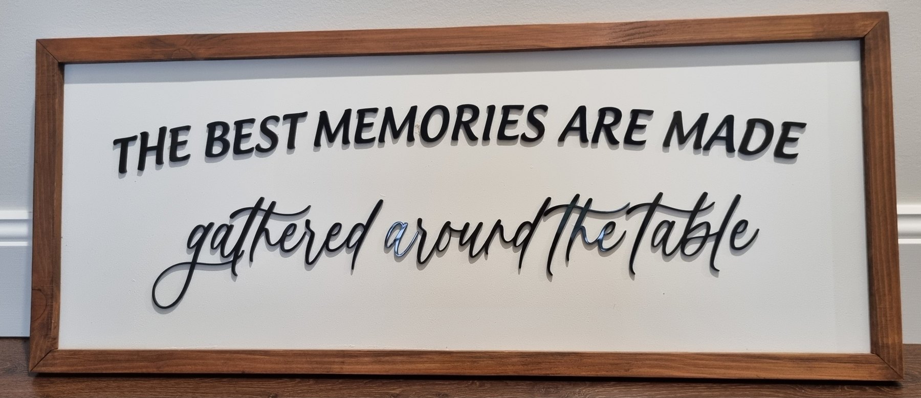 Framed timber sign reading The best memories are made gathered around the table